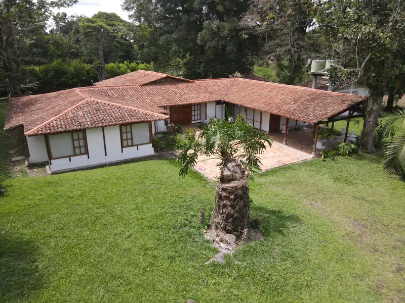Casa campestre de Bélgica Lux con aleros amplios y vegetación alrededor, sobre la vía Cerritos